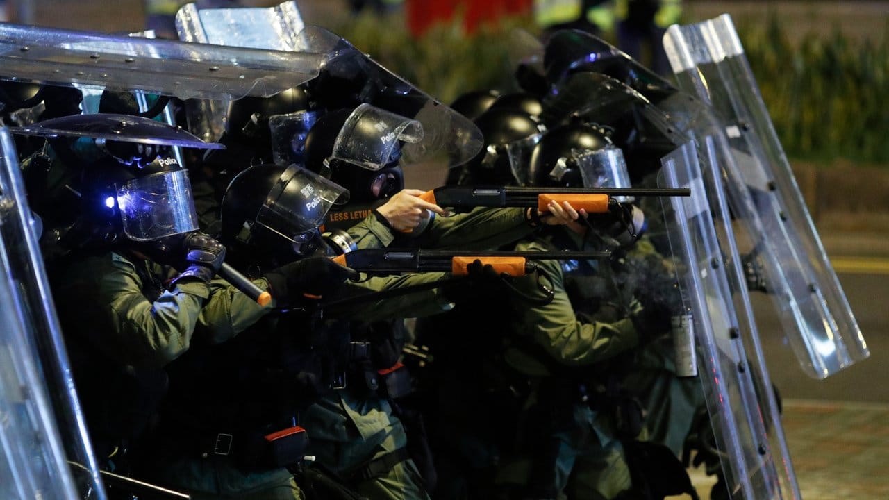 Polizisten richten Waffen auf Demonstranten.