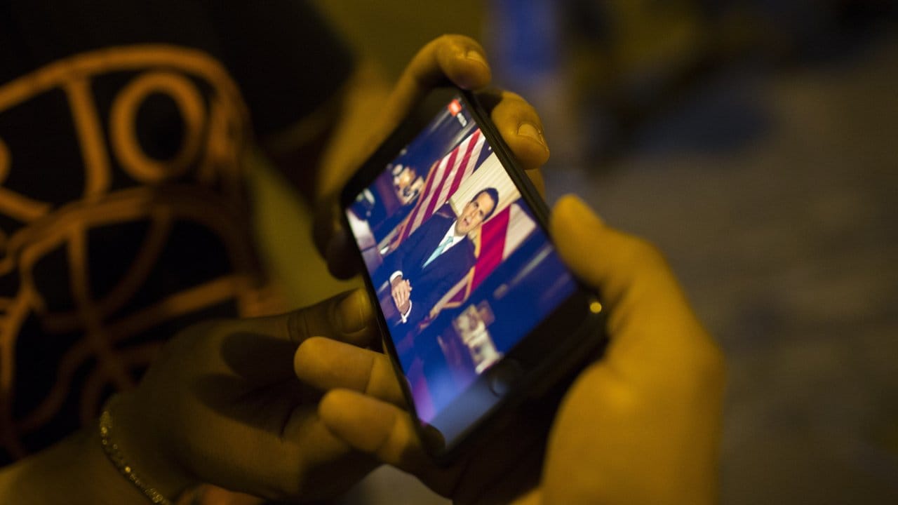 Puerto-Ricaner verfolgen auf einem Smartphone eine Videoaufzeichnung, in der Gouverneur Rosselló seinen Rücktritt zum 2.