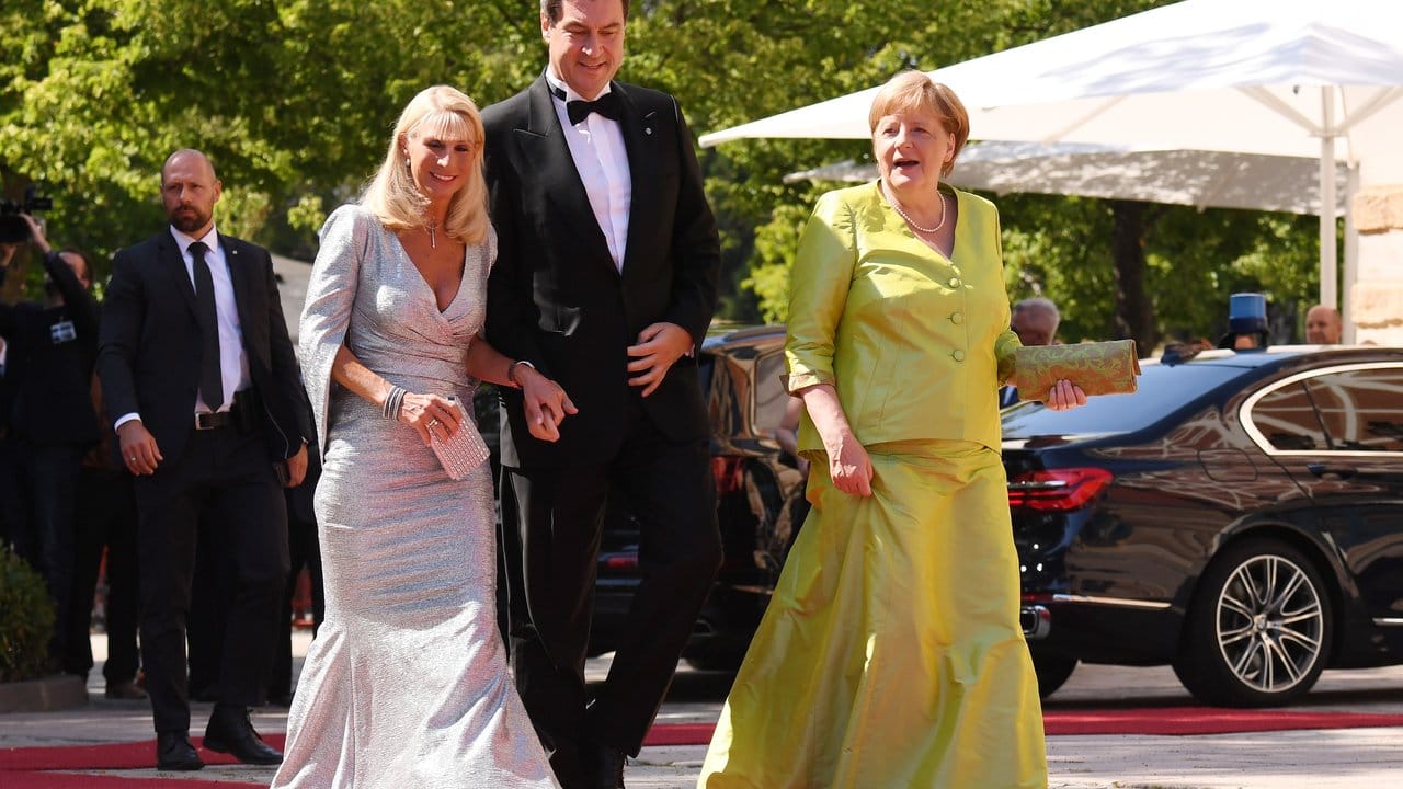 Bundeskanzlerin Angela Merkel schreitet mit dem Bayerischen Ministerpräsidenten Markus Söder und dessen Frau, Karin Baumüller-Söder, über den roten Teppich. Bundeskanzlerin Angela Merkel schreitet mit dem Bayerischen Ministerpräsidenten Markus Söder und dessen Frau, Karin Baumüller-Söder, über den roten Teppich.