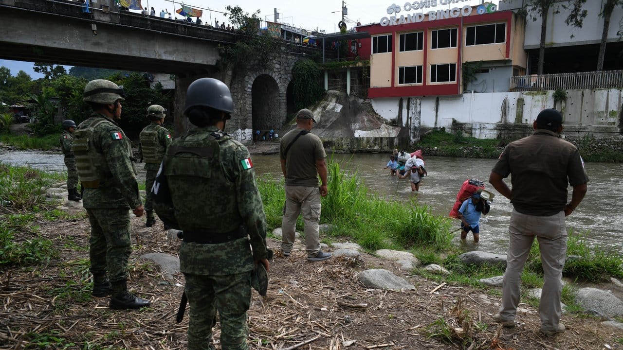Mexikanische Soldaten und Einwanderungsbeamte beobachten Migranten aus Guatemala beim Versuch, durch einen Fluss illegal einzuwandern.