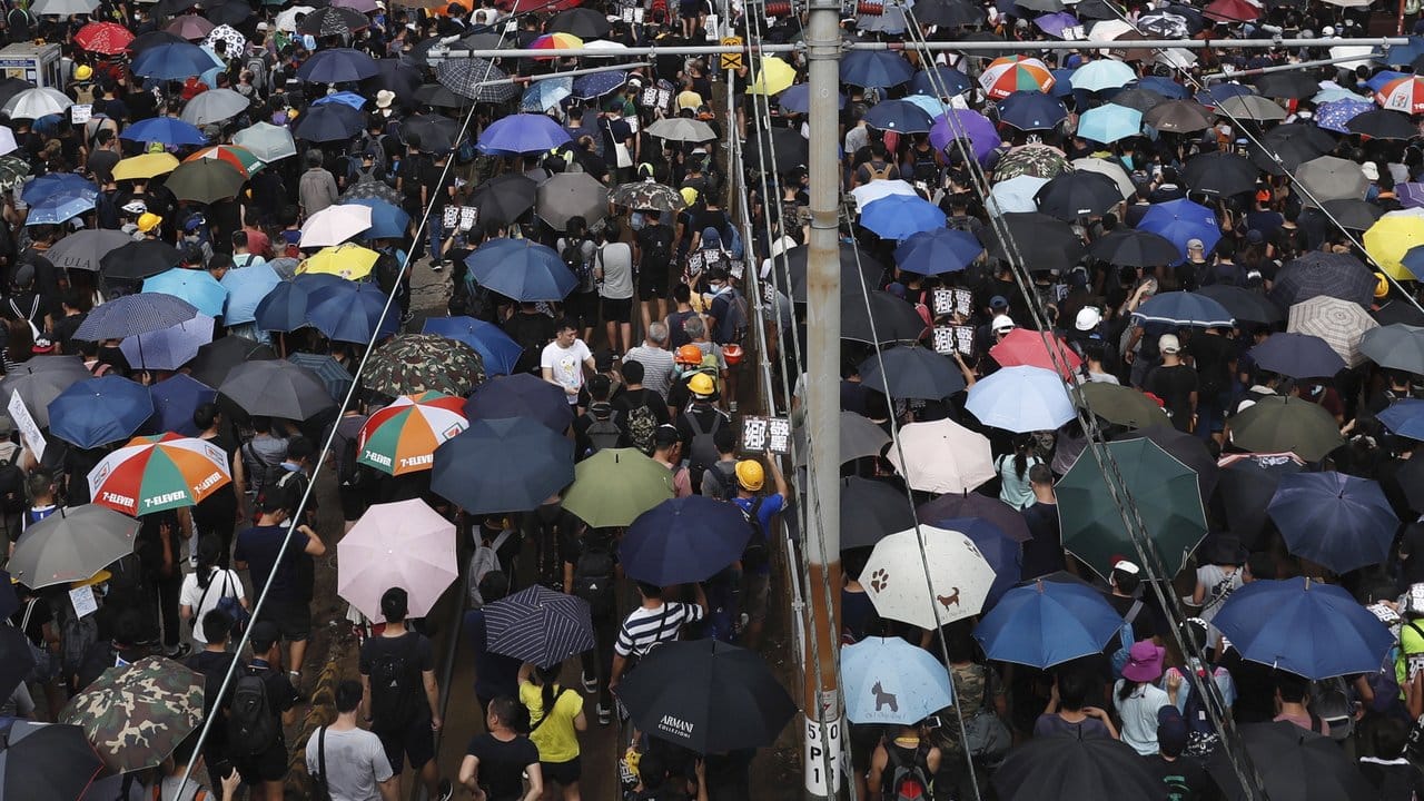Mit Regenschirmen protestieren Hongkonger gegen die Regierung und einen Angriff von Schlägertrupps eine Woche zuvor.