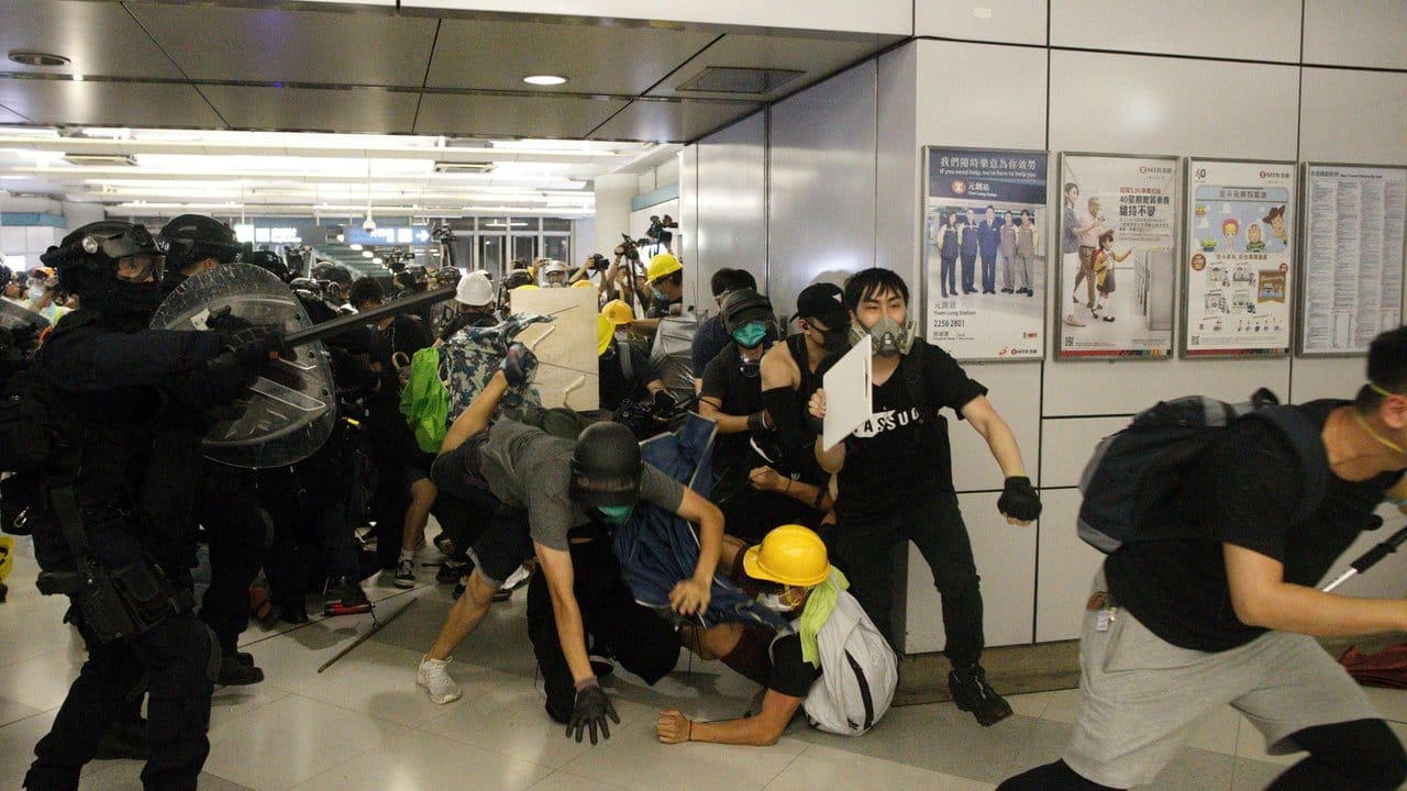 Eine Spezialeinheit der Polizei greift Demonstranten mit Schlagstöcken an, die sich weigern einen Bahnhof zu verlassen.