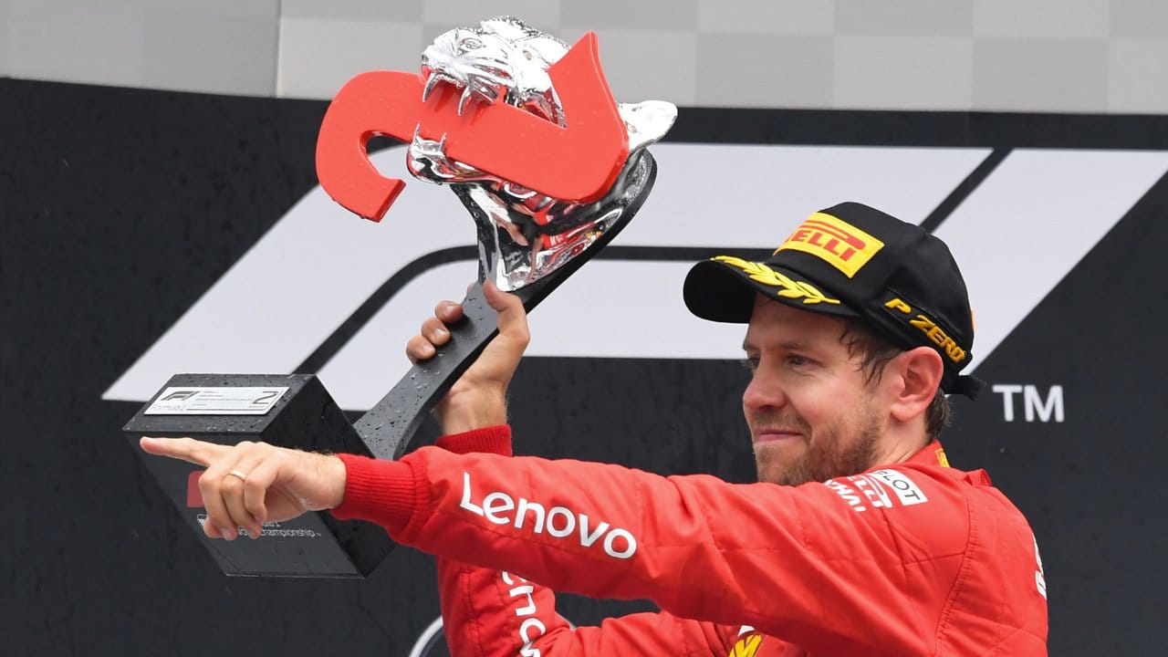 Vettel jubelt bei der Siegerehrung mit der Trophäe.