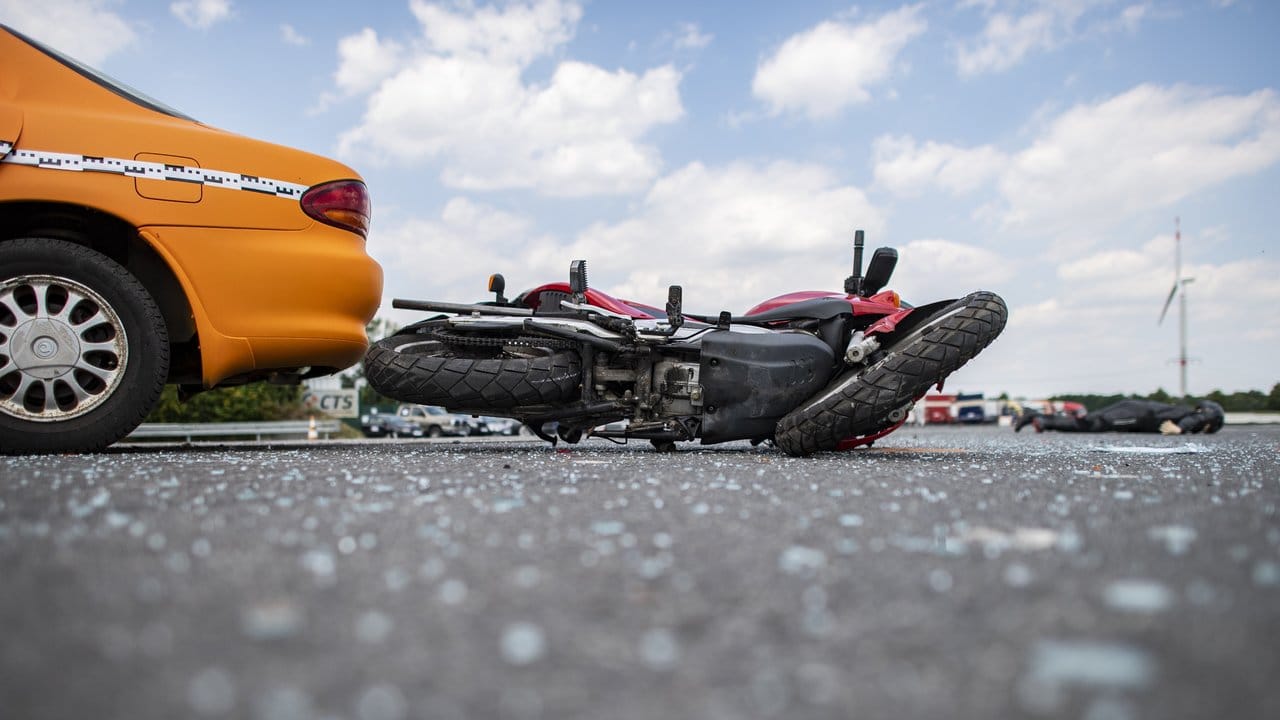 Ein Motorrad liegt nach einem Crashtest der Unfallforscher neben einem Auto auf der Straße.
