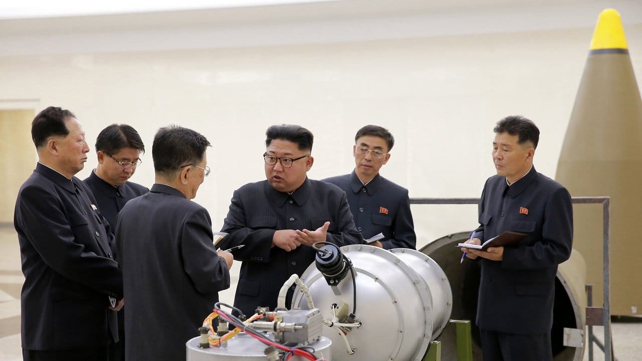 Nordkoreas Staatschef Kim Jong Un neben einem Sprengkopf.