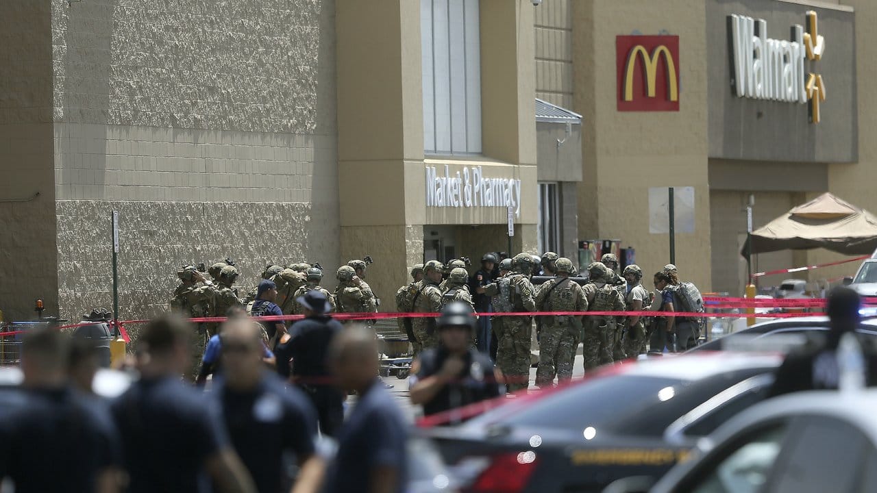 Mitglieder einer Spezialeinheit und Polizisten vor dem Eingang des Einkaufszentrums, in dem der Täter zahlreiche Menschen erschossen hat.