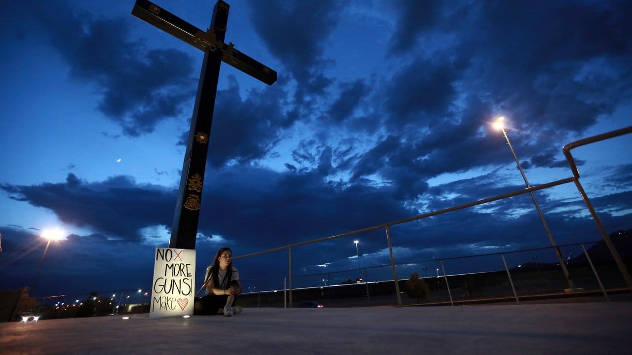 Eine Frau sitzt in El Pasos mexikanischer Nachbarstadt Juarez neben einem Schild mit der Aufschrift "No more Guns, make Love".