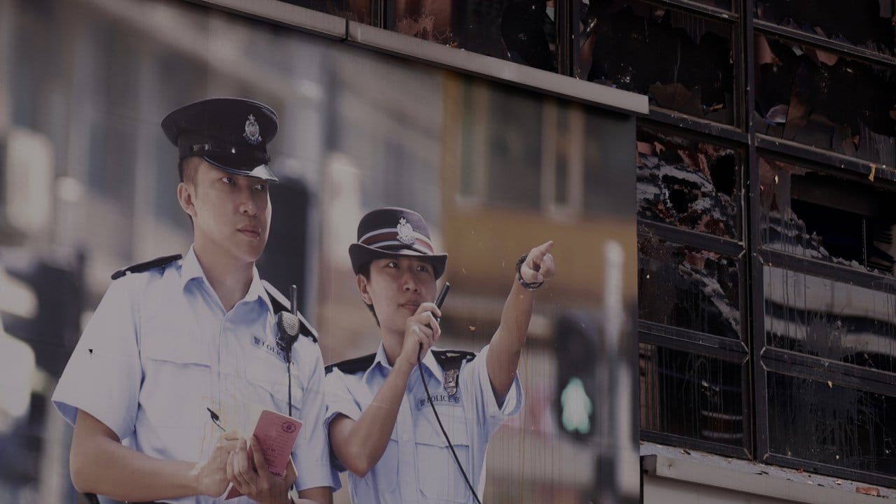 Ein Werbeplakat der Polizei hängt vor einer zerstörten Polizeistation.