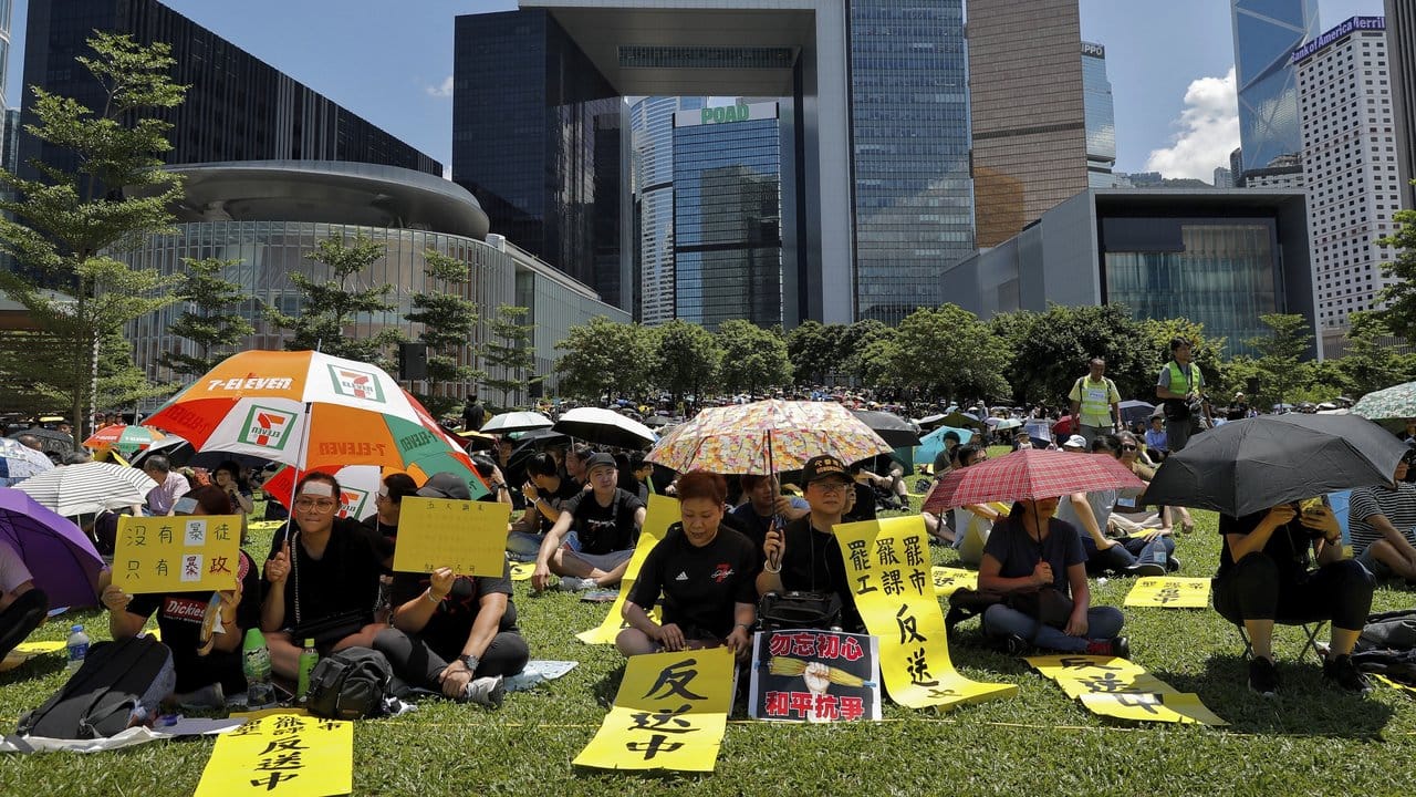 Demonstranten im Tamar Park halten Regenschirme und Plakate mit Slogans wie "Anti-Auslieferungsgesetz" und "Streik".