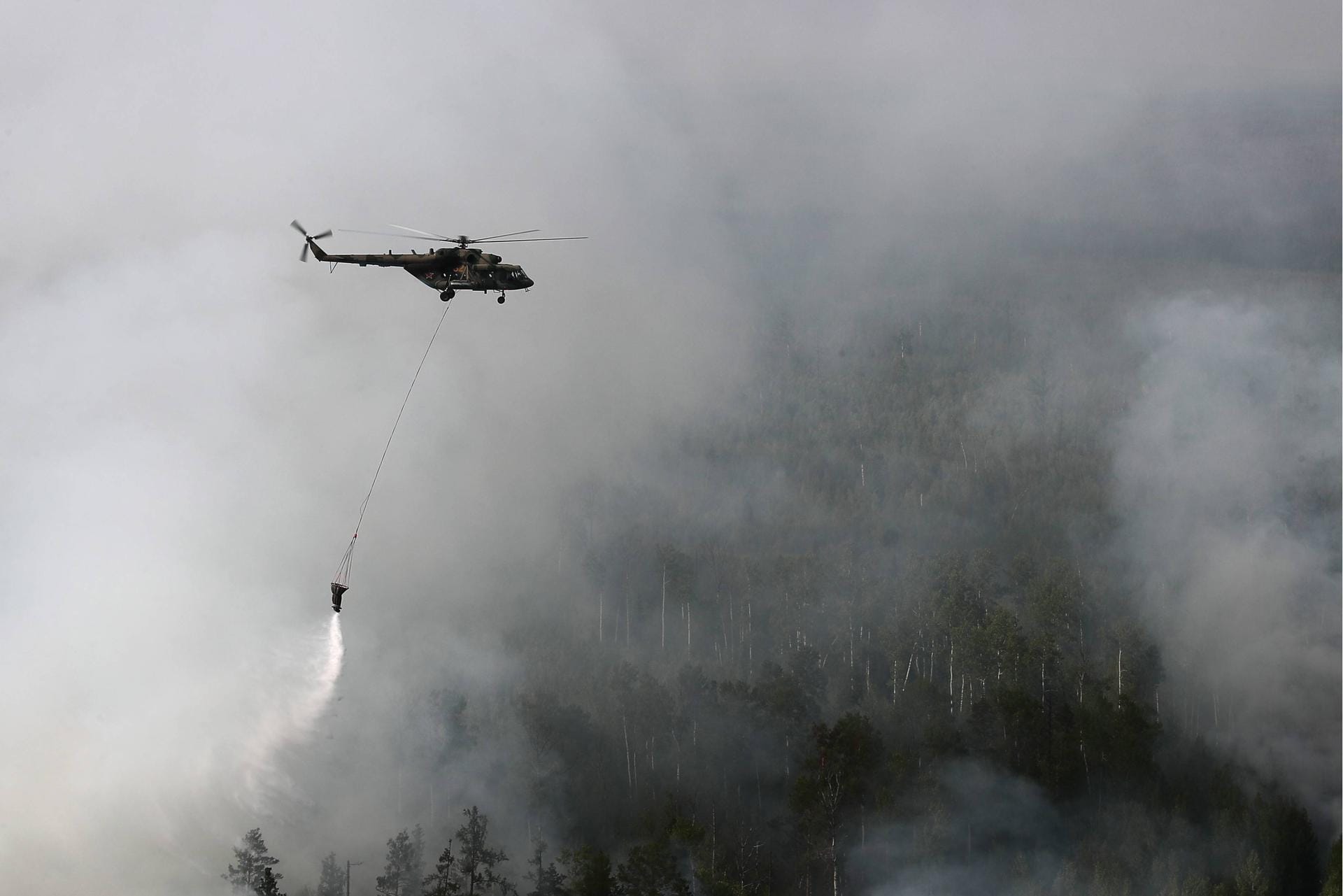 Im Kampf gegen das Feuer wirft ein Helikopter Wasser auf die Brände ab: Seit das Militär sich an dem Kampf gegen das Feuer beteiligt, gibt es erste Erfolge – doch es geht zu langsam voran.