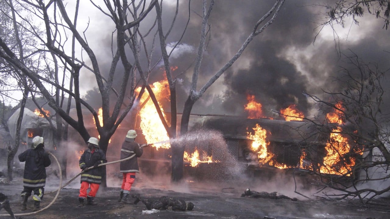 Feuerwehrleute versuchen den Brand des umgestürzten Tanklasters zu löschen.