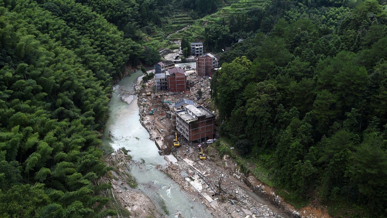 Nach einem Erdrutsch durch den Taifun "Lekima" sind Erdmassen und Wasser zwischen Häusern neben einem Waldgebiet zu sehen.
