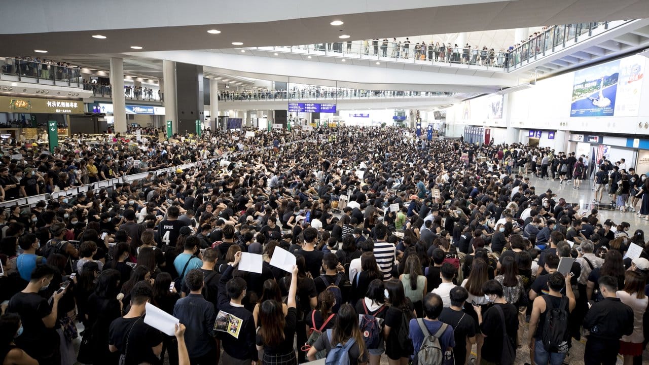 Demonstranten protestieren in der Ankunftshalle des Flughafens gegen die Regierung und die Polizeigewalt bei vergangenen Protesten.