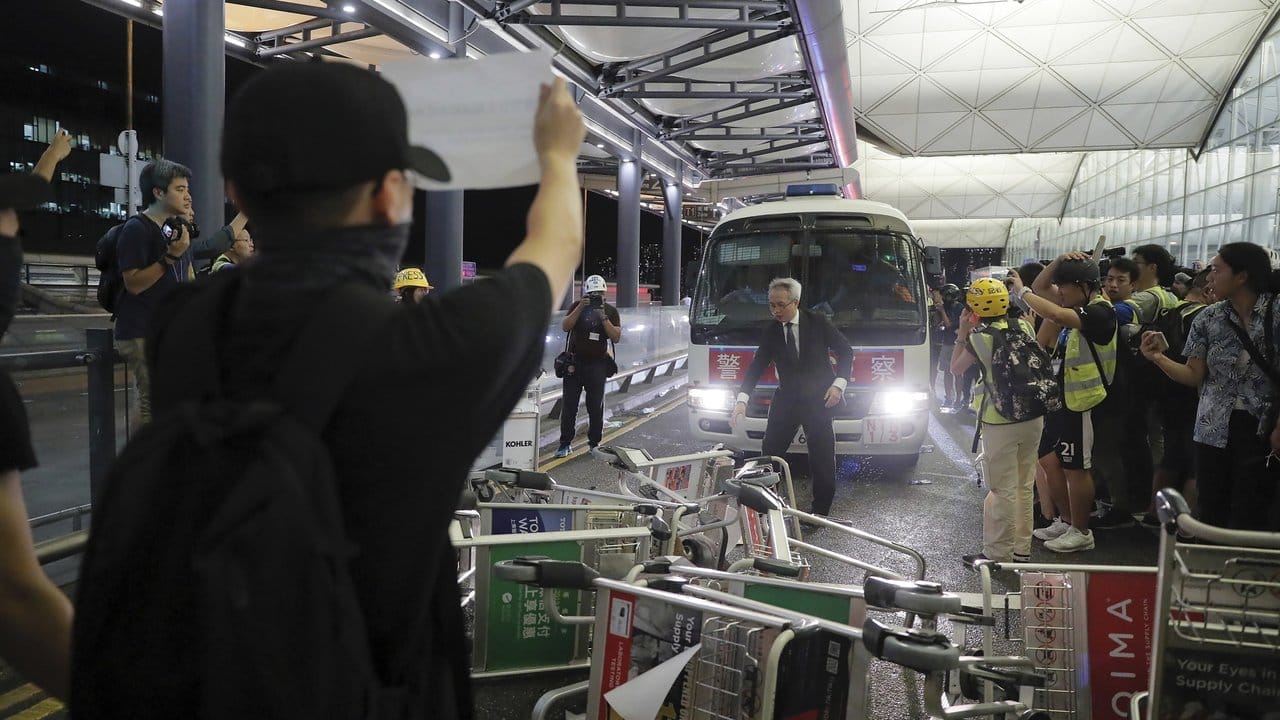 Demonstranten stellen sich am Flughafen von Hongkong einem Polizeiwagen in den Weg.