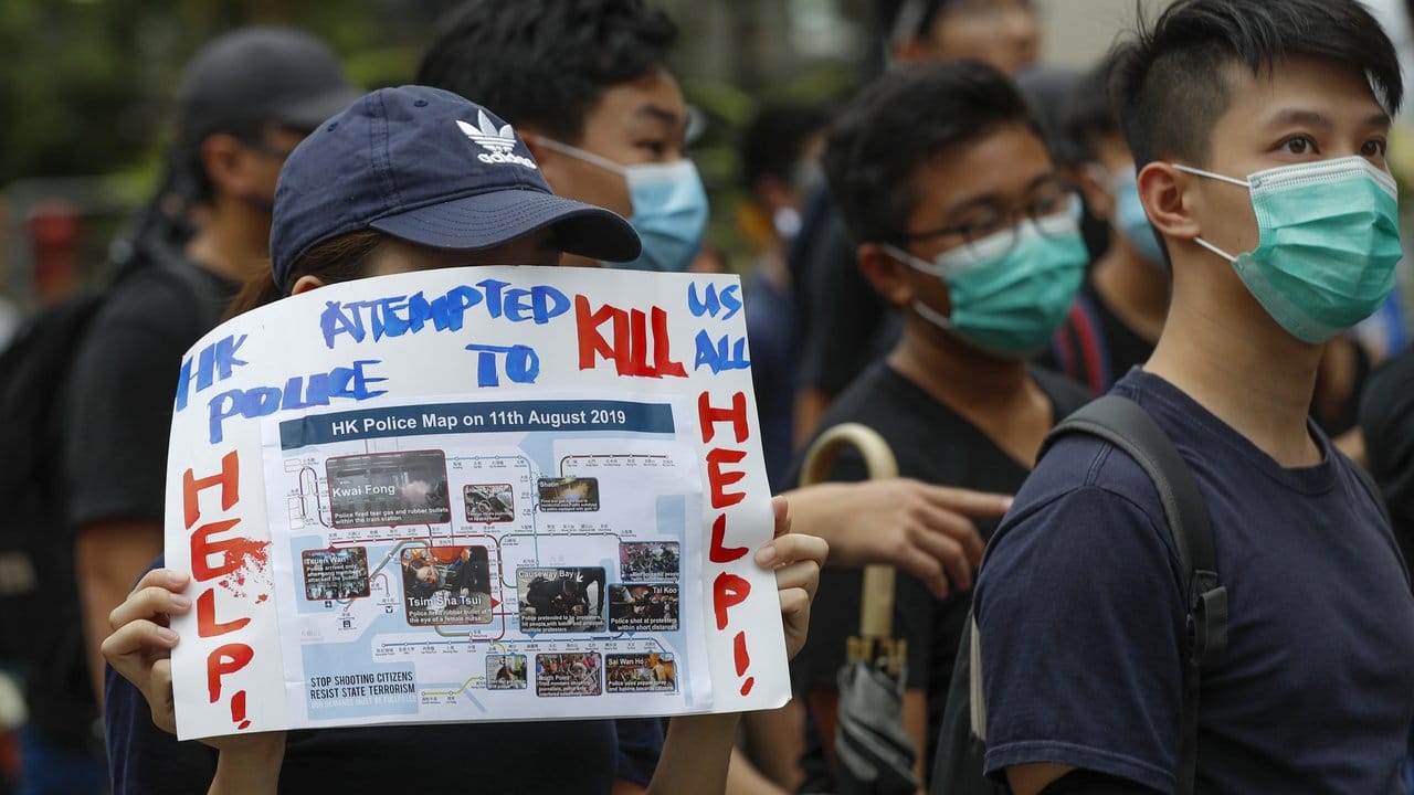 Eine Demonstrantin hält während eines Protests ein Plakat gegen Gewalt in den Händen.