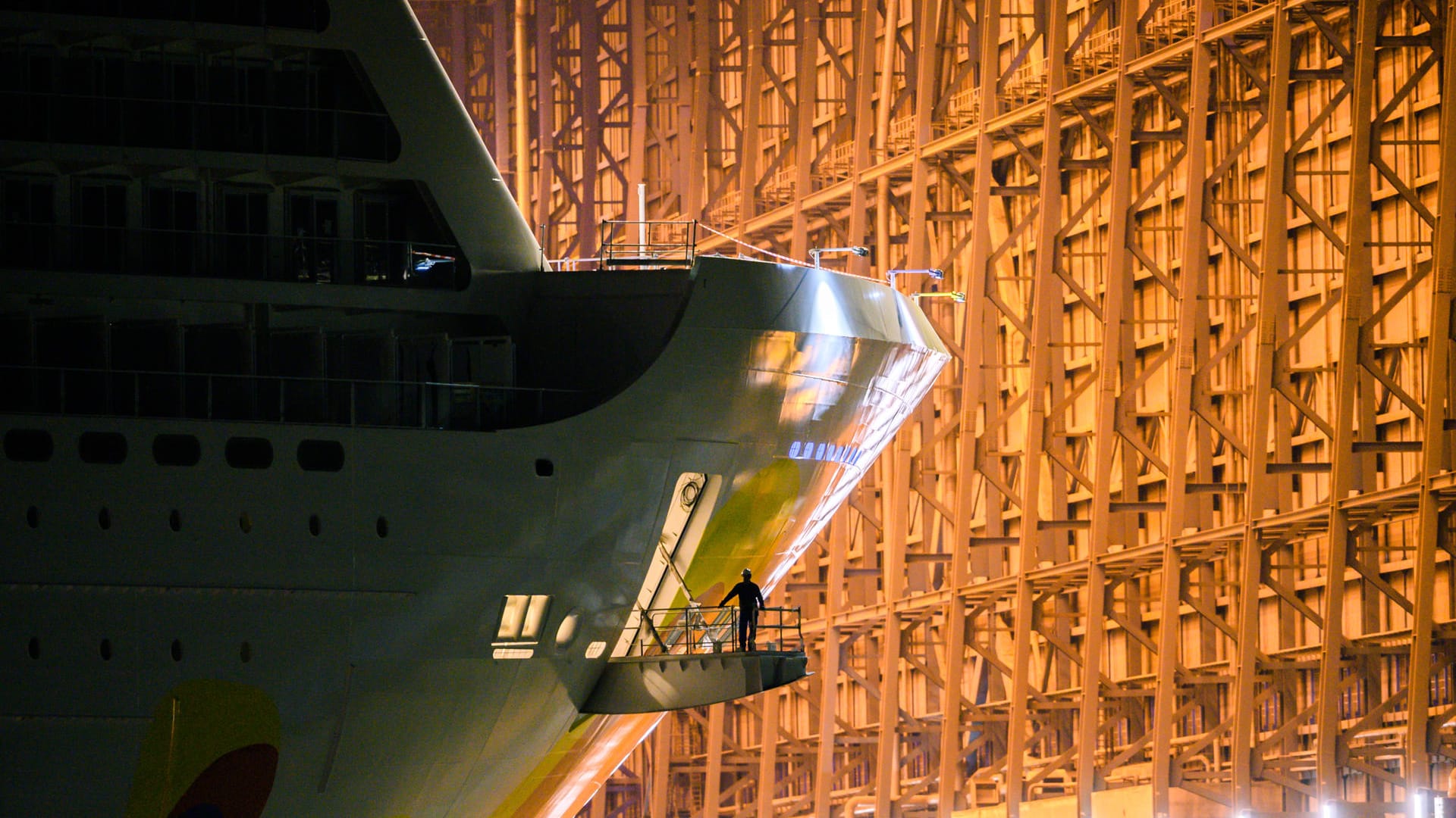 Ein Arbeiter steht an einer Öffnung am Bug des Kreuzfahrtschiffs "Norwegian Encore", während es das Baudock der Meyer Werft verlässt: Das Schiff ist 330 Meter lang.