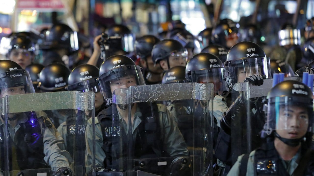 Polizisten in Schutzausrüstung blockieren während eines Protestmarschs prodemokratischer Demonstranten eine Straße.