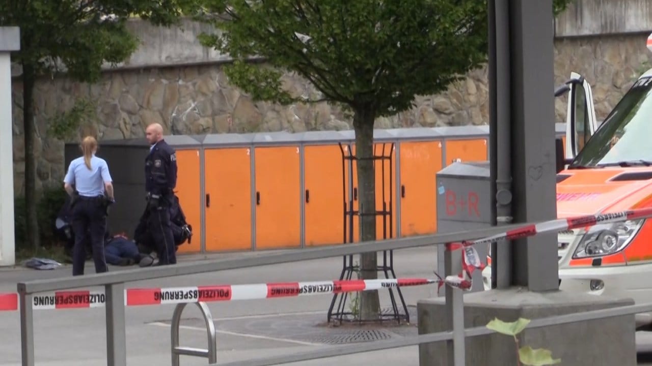 Polizisten am Stadtbahnhof in Iserlohn neben dem am Boden liegenden Tatverdächtigen.