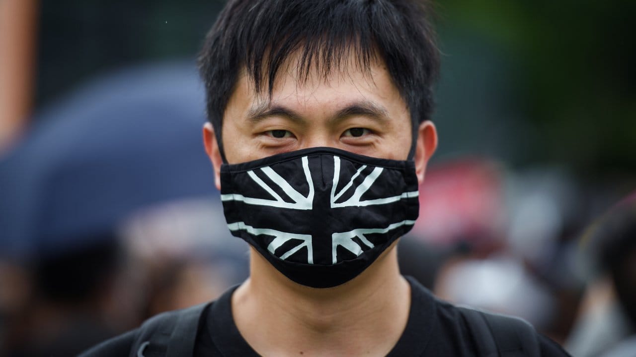 Ein Demonstrant trägt auf dem zentralen Ort der Kundgebung im Victoria Park einen Mundschutz mit der britischen Flagge.