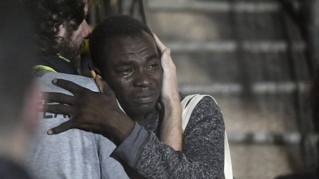 Ein Mann umarmt weinend ein Besatzungsmitglied, nachdem auf Lampedusa angekommen ist.