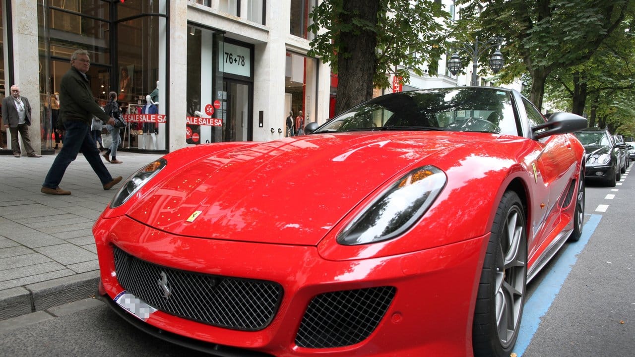 Ein Ferrari parkt auf der Königsallee in Düsseldorf, die als Laufsteg der Reichen und Schönen gilt.