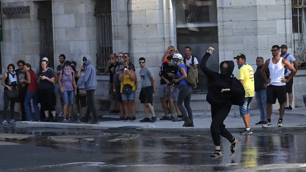 Eine Demonstrantin wirft in Bayonne einen Stein in Richtung Polizei.