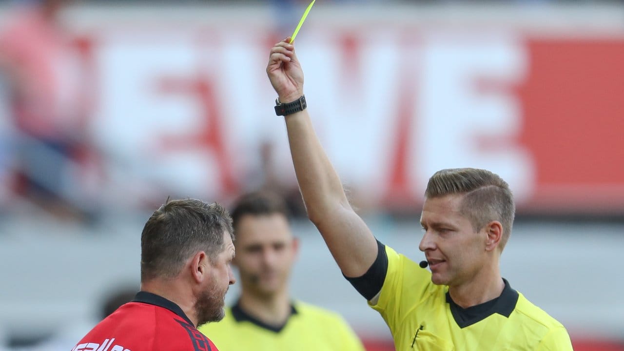 Schiedsrichter Tobias Welz (r) zeigt Paderborn-Trainer Baumgart (l) die erste Gelbe Karte.