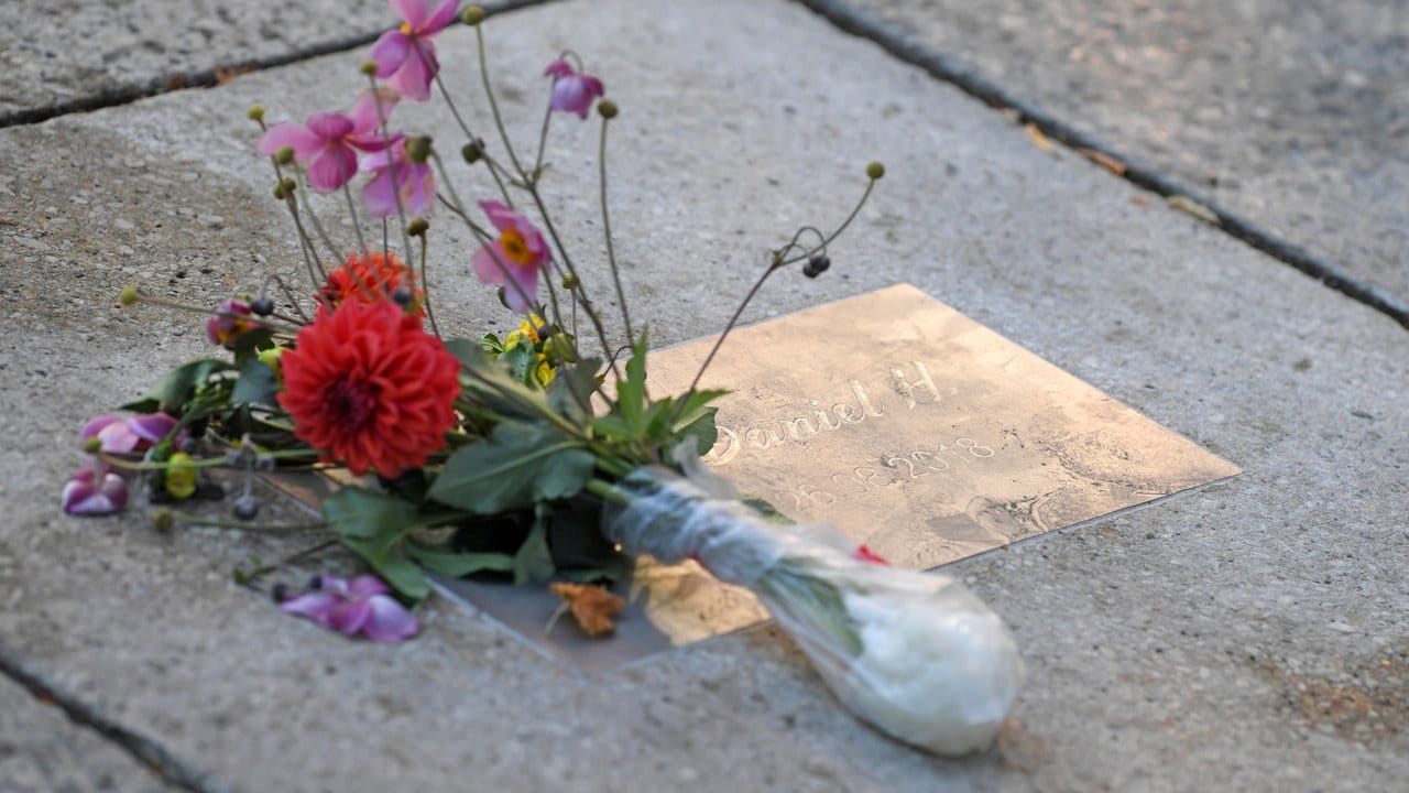 Blumen liegen an einer Gedenkplatte für den getöteten Daniel H.