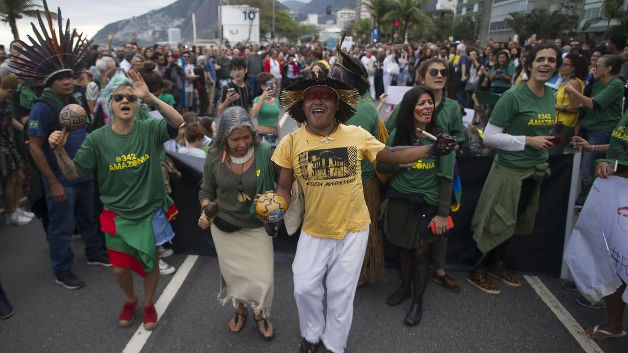 Tanzend demonstrieren Menschen in Rio de Janeiro gegen die Umweltpolitik von Präsident Bolsonaro.