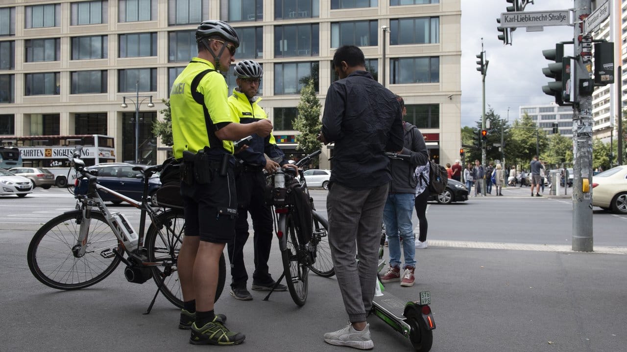 Und noch eine neue Aufgabe: Polizisten der Berliner Fahrradstaffel kontrollieren auf einem Bürgersteig zwei Jugendliche mit E-Tretrollern.