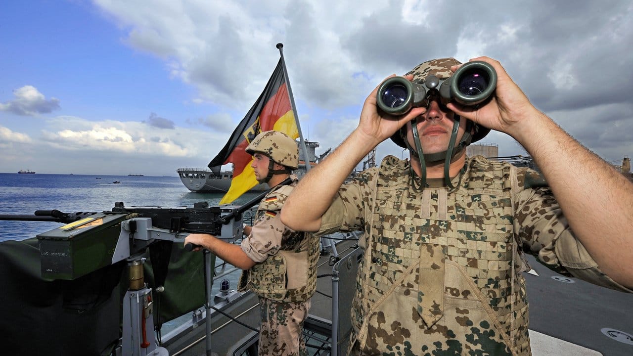 Deutsche Marine-Soldaten halten an Bord der Fregatte "Karlsruhe" an einem Maschinengewehr Wache.