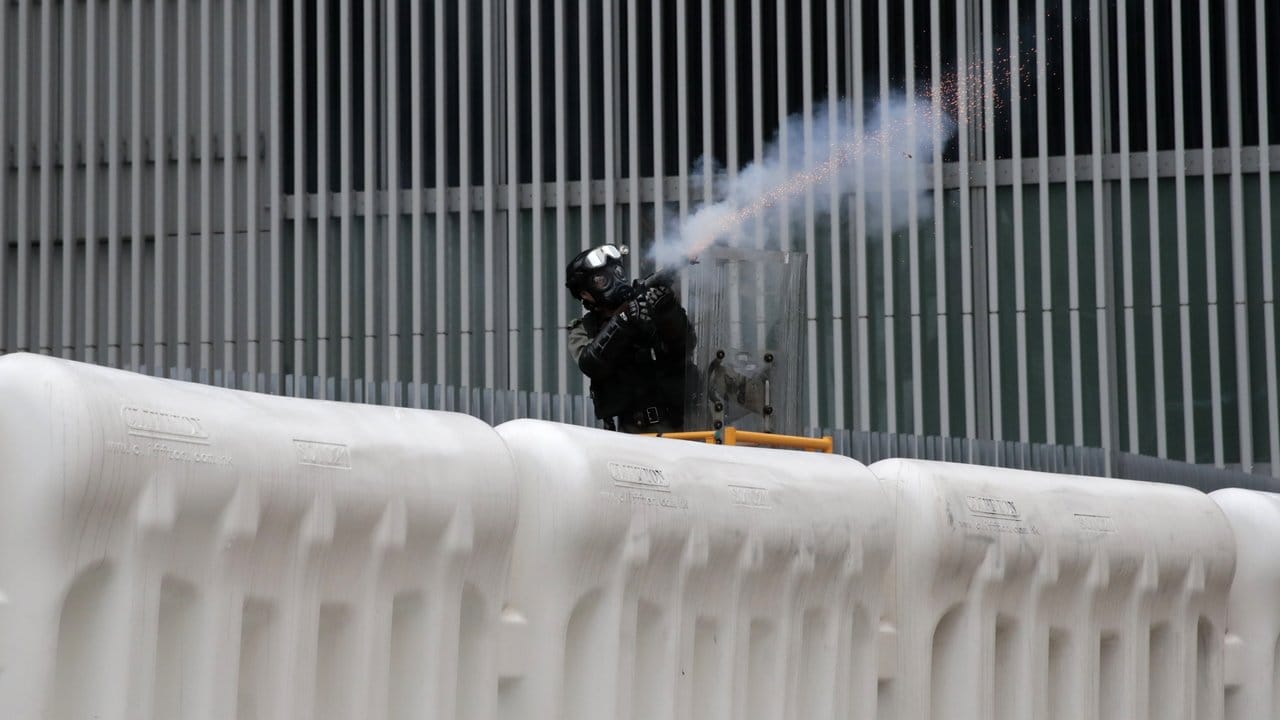 Ein Polizist feuert eine Tränengasgranate auf Demonstranten ab.