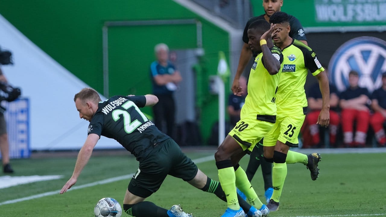 Wolfsburgs Maximilian Arnold (l) fällt im Zweikampf mit Paderborns Streli Mamba.