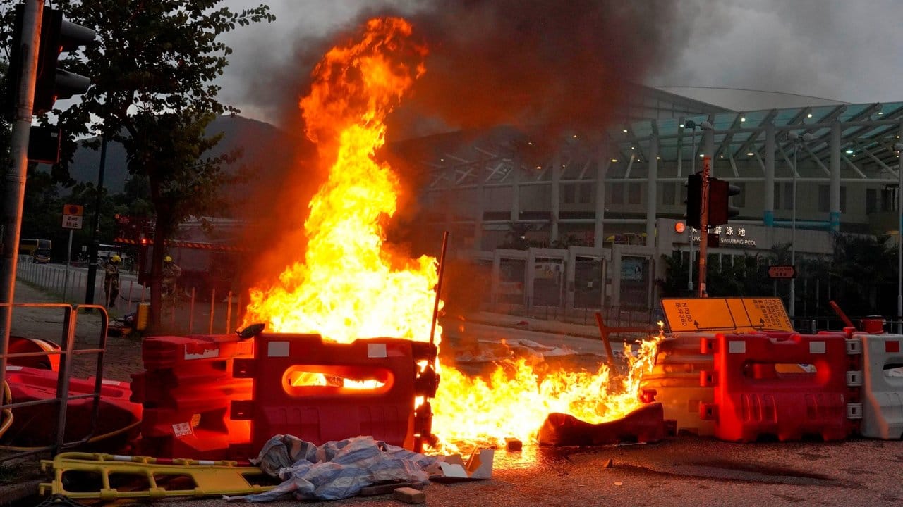 Von prodemokratischen Demonstranten vor dem Flughafen errichtete Barrikaden stehen in Flammen.