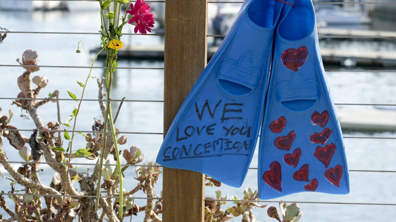 Ein Paar Flossen und Blumen hängen an einem Zaun im Hafen von Santa Barbara in Gedenken an die Opfer des Bootsfeuers.
