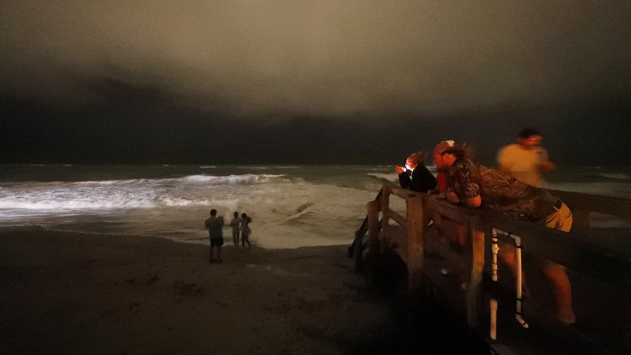 Beobachter stehen nachts auf einer Promenade entlang des Atlantiks, während die ersten Ausläufer des Hurrikans Dorian näher kommen. Beobachter stehen nachts auf einer Promenade entlang des Atlantiks, während die ersten Ausläufer des Hurrikans Dorian näher kommen.