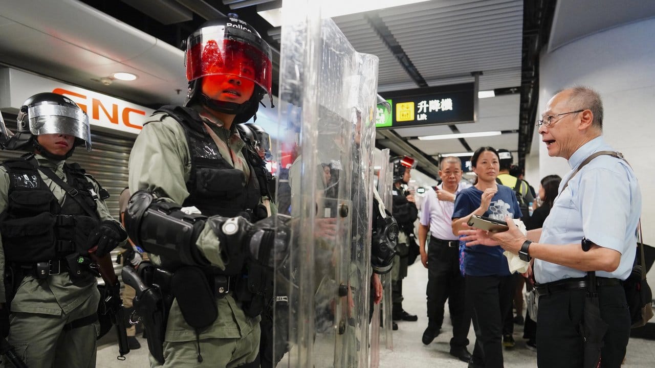 Versuch eines Gesprächs: Ein älterer Mann streitet sich mit Polizisten am Hongkonger Hauptbahnhof.