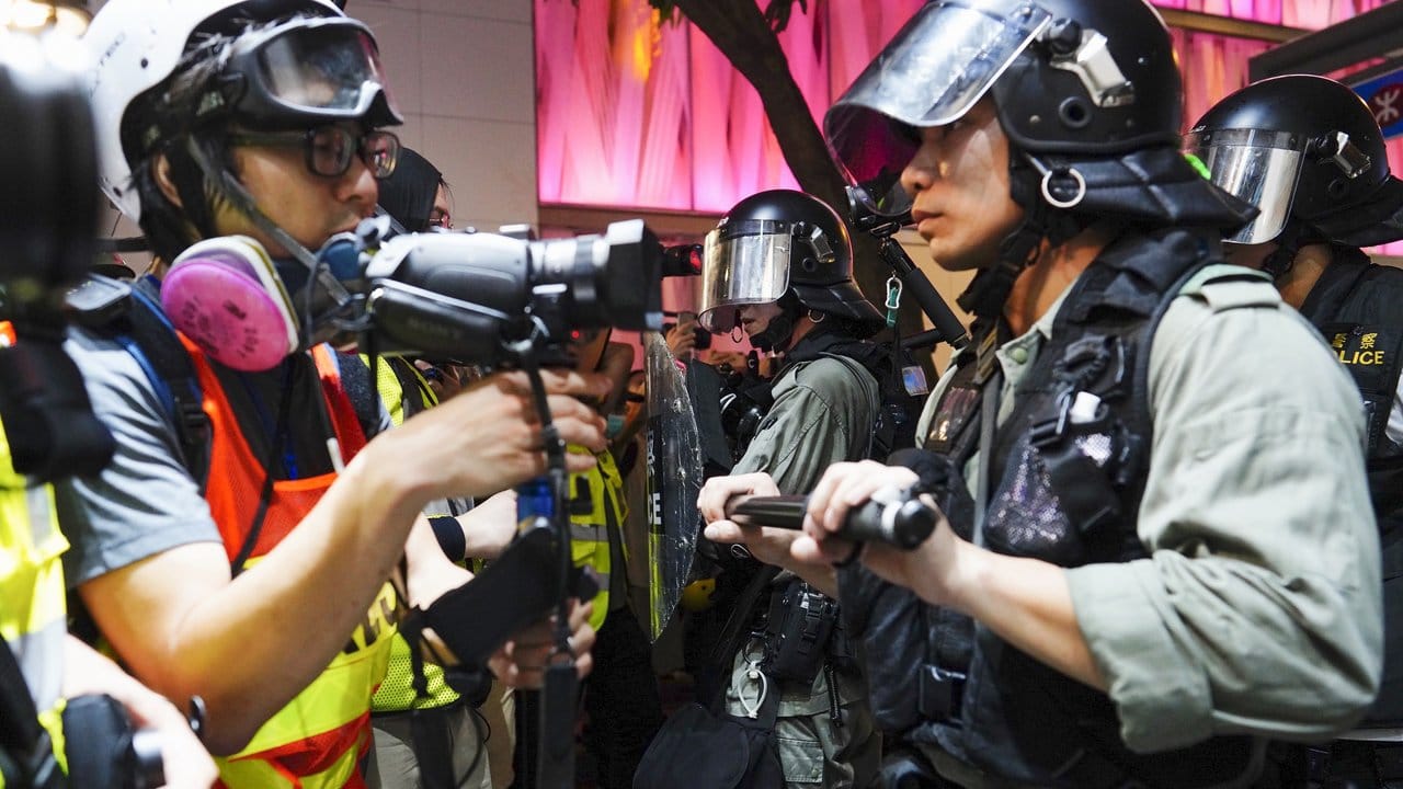 Polizisten halten Journalisten zurück, während weitere Polizisten Demonstranten festsetzen.