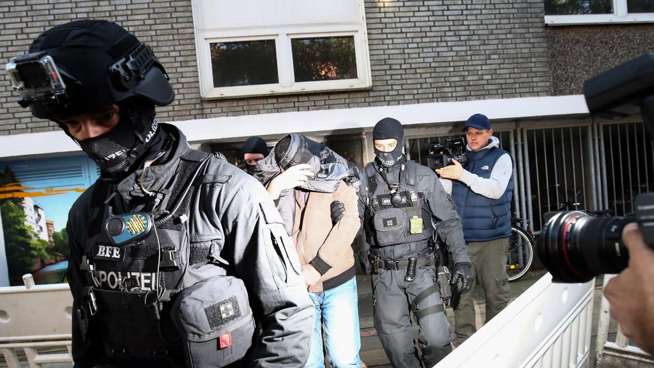 Terror-Razzia in Hamburg: Ein Mann wird von Polizisten aus einem Haus geführt.