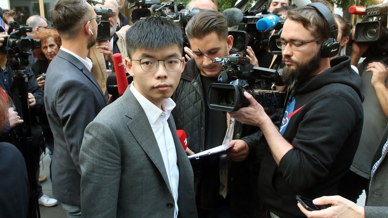 Joshua Wong wird nach seiner Pressekonferenz in Berlin von Medienvertretern umringt.