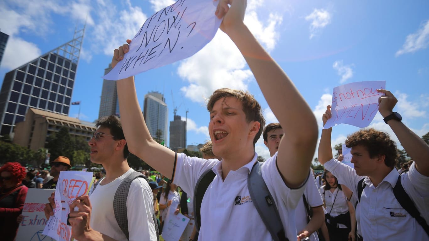 Australien, Sydney: Demonstranten mit Plakaten nehmen am globale Streik für mehr Klimaschutz teil.