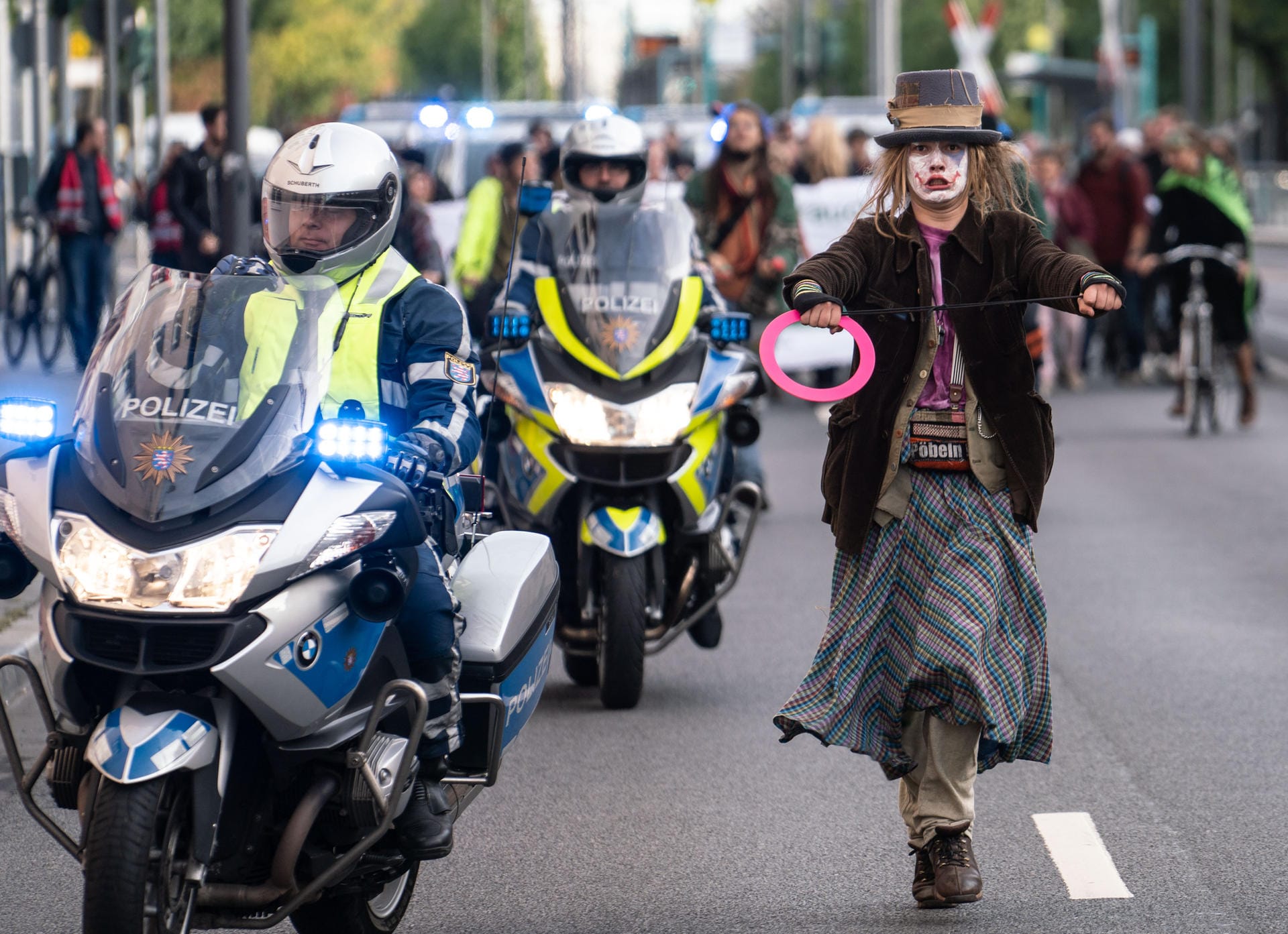 Eine als Gauckler verkleidete Demonstratin imitiert bei einer Blockade der Friedberger Landstraße in Frankfurt im morgendlichen Berufsverkehr einen Motorradfahrer der Polizei.
