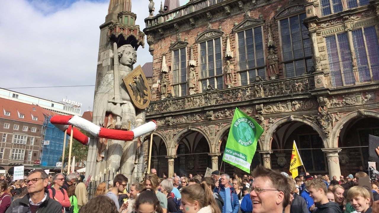 Demonstranten stehen vor dem historischen Rathaus und dem Roland in Bremen.