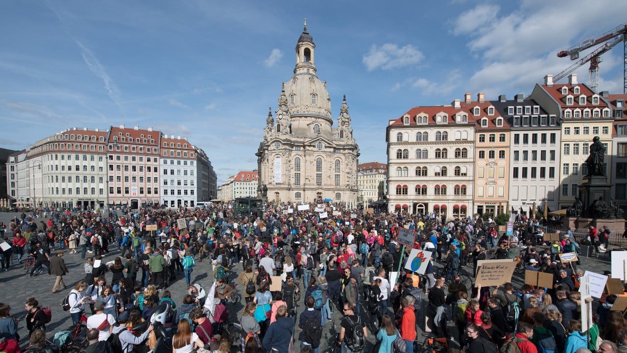 Demonstranten stehen in Dresden mit Schildern und Transparenten auf dem Neumarkt vor der Frauenkirche.