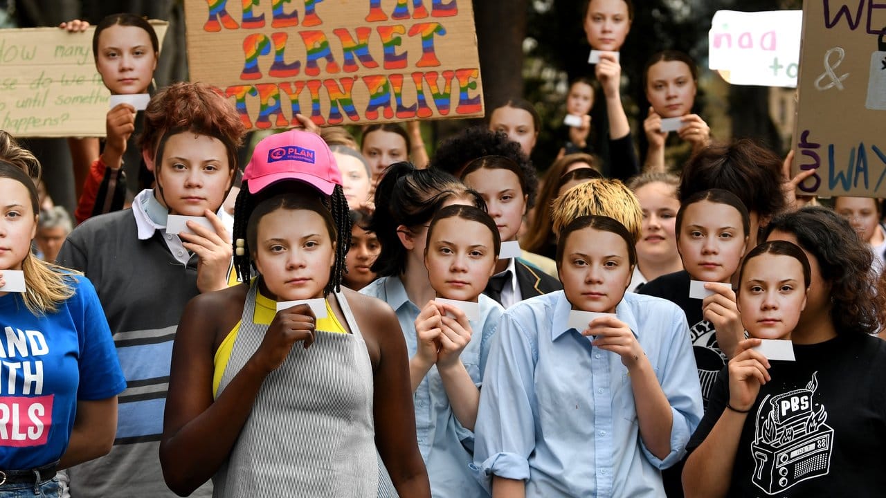 Greta Thunberg überall: Teilnehmer der Demonstration in Melbourne halten Masken mit dem Gesicht der schwedischen Umweltaktivistin vor ihre Gesichter.