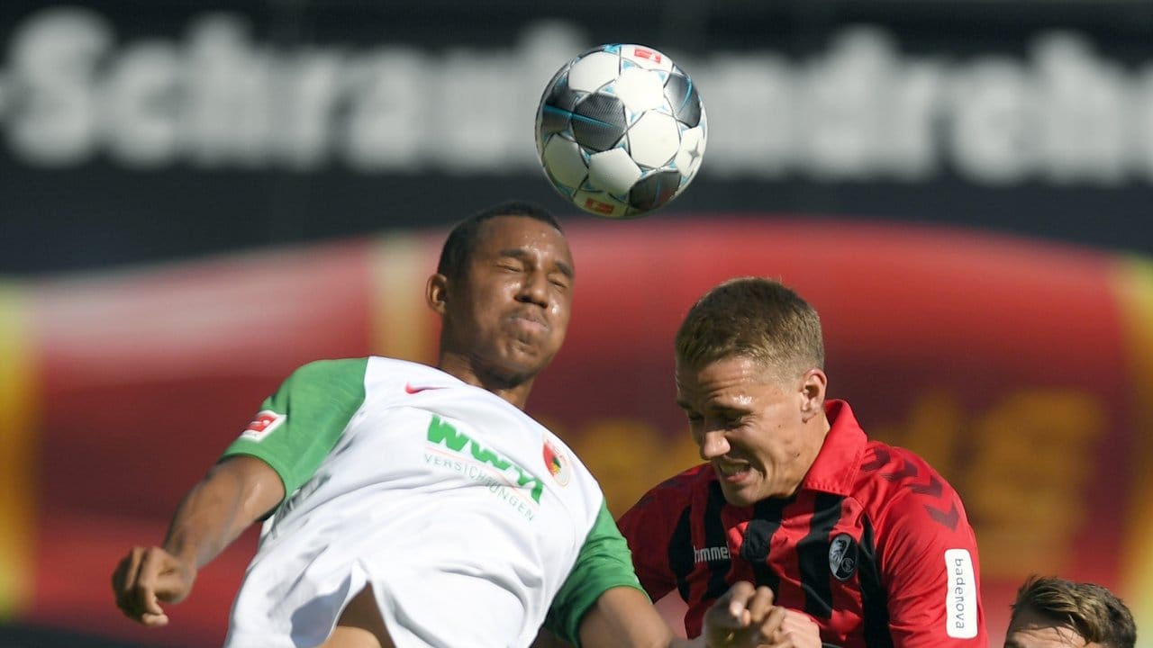 Der Augsburger Ohis Felix Uduokhai (l) und Nils Petersen vom SC Freiburg gegen zum Ball.
