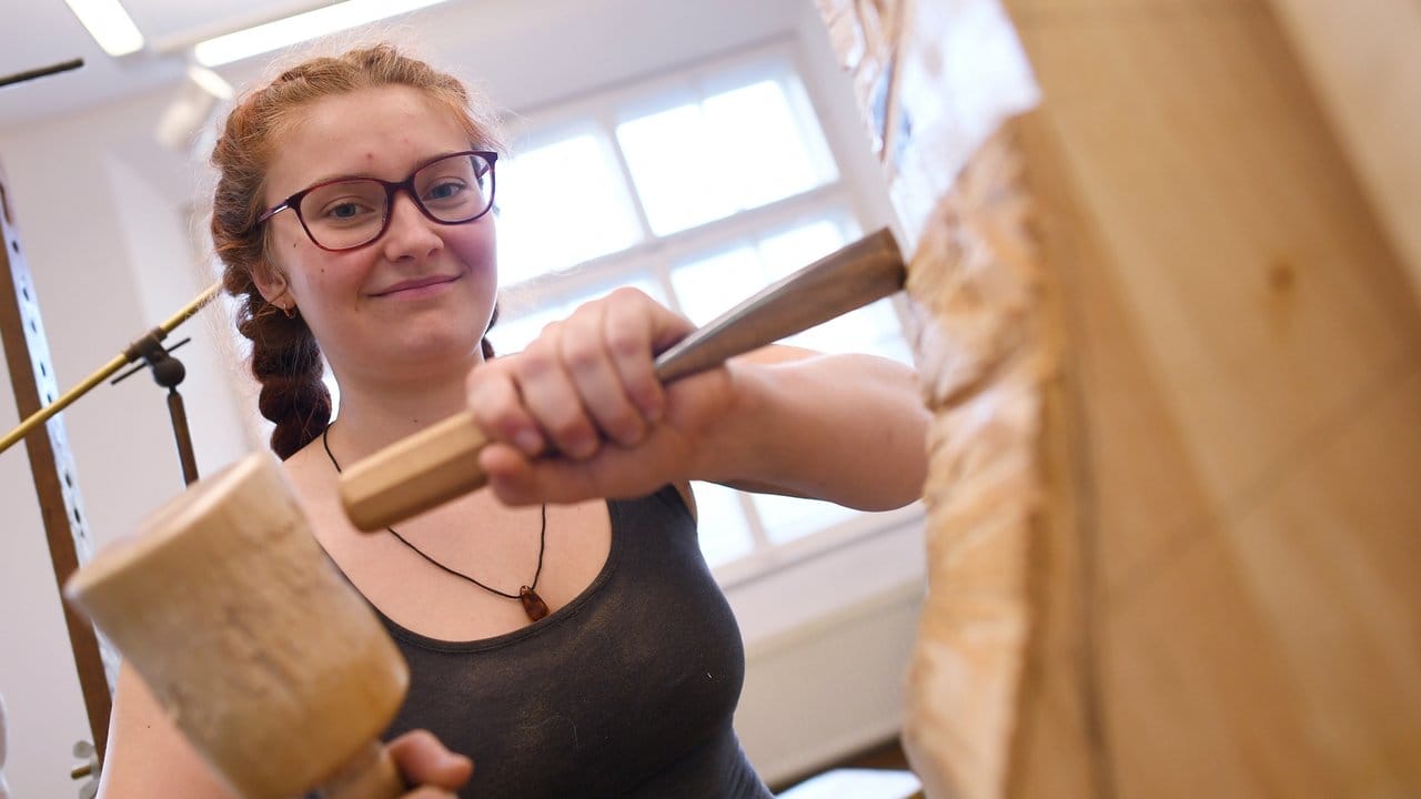 Sophia Böhner erlernt ein traditionelles Handwerk: Mit Bildhauereisen und Klüpfel bearbeitet die angehende Holzbildhauerin ein Objekt.