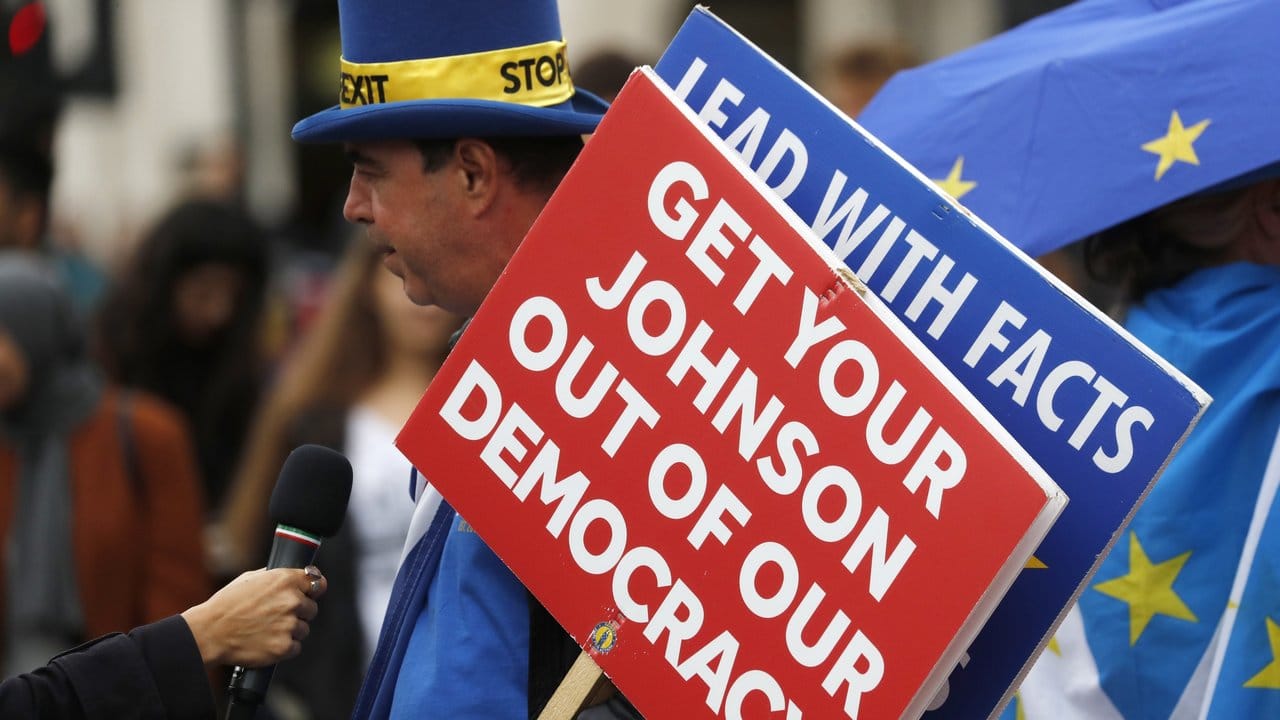 Ein Brexit-Gegner spricht vor dem Parlament zu Journalisten und hält ein Schild mit der Aufschrift "Get your Johnson out of our democracy" (Entfernt euren Johnson aus unserer Demokratie).