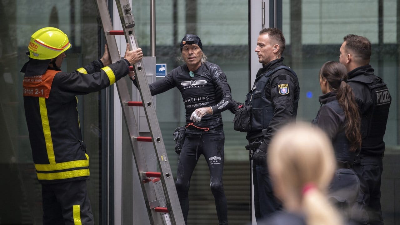 Nachdem er die Fassade des Skyper-Hochhauses wieder hinuntergeklettert war, wird der Extremkletterer von Polizisten in Empfang genommen. Nachdem er die Fassade des Skyper-Hochhauses wieder hinuntergeklettert war, wird der Extremkletterer von Polizisten in Empfang genommen.
