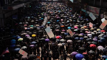 Zehntausende Demonstranten marschieren durch Hongkong, zumeist schwarz gekleidet und mit Regenschirmen.